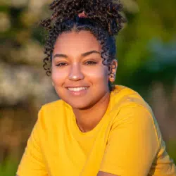 Laura B, Avon Rep Head shot, smiling outside in a bright yellow top